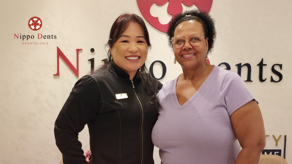 Foto de paciente sorrindo ao lado da Dra. Claudine após tratamento com implantes